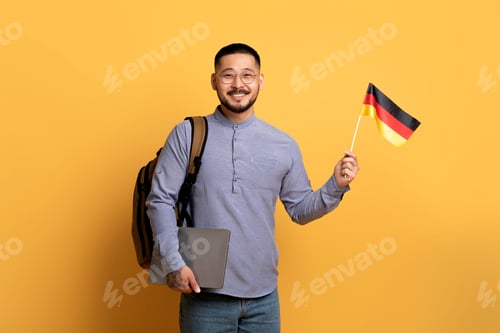 Preview: Online Language Courses. Smiling Young Asian Man Holding German Flag And Laptop