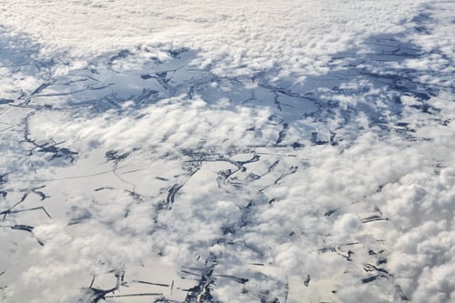 Preview: Aerial view over clouds top to snow covered rivers, fields and roads, winter fresh frosty air