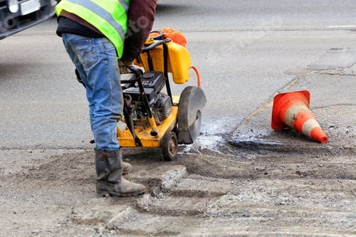Preview: A road maintenance worker removing old asphalt with gasoline carver during repairs on a carriageway