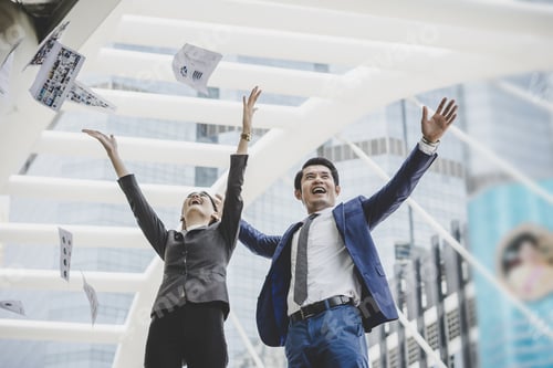 Preview: Business people are throwing up papers, while standing in front of office building.