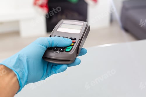 Preview: hand in gloves and pos terminal, successful contactless payment.