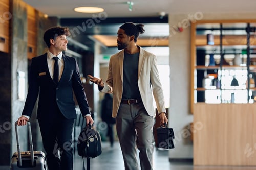 Preview: Happy receptionist and black man communicating while walking through hotel hallway.