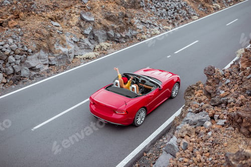 Preview: Woman driving red cabriolet on the volcanic valley