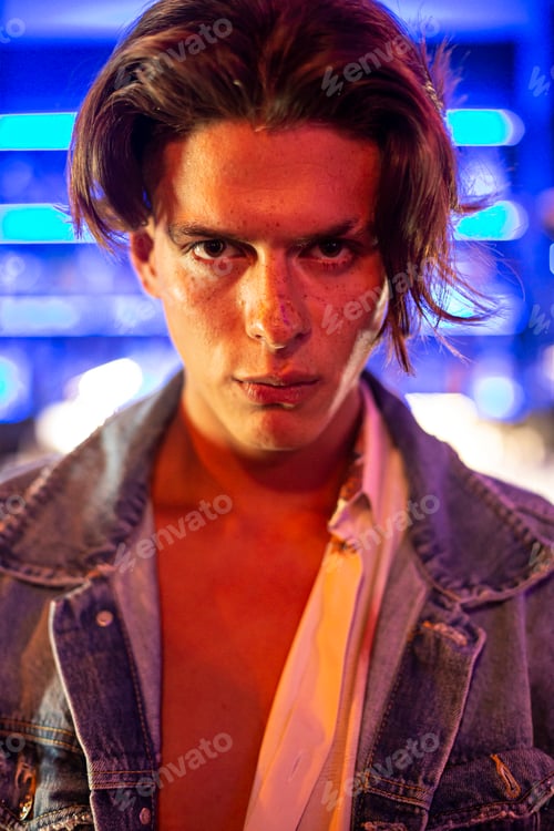 Preview: Close-up portrait of young man in jean jacket with bar background.