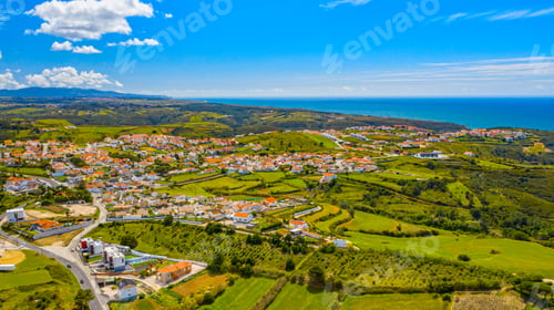 Preview: Small european village on a green valley with ocean on background. Aerial view to scenic urban