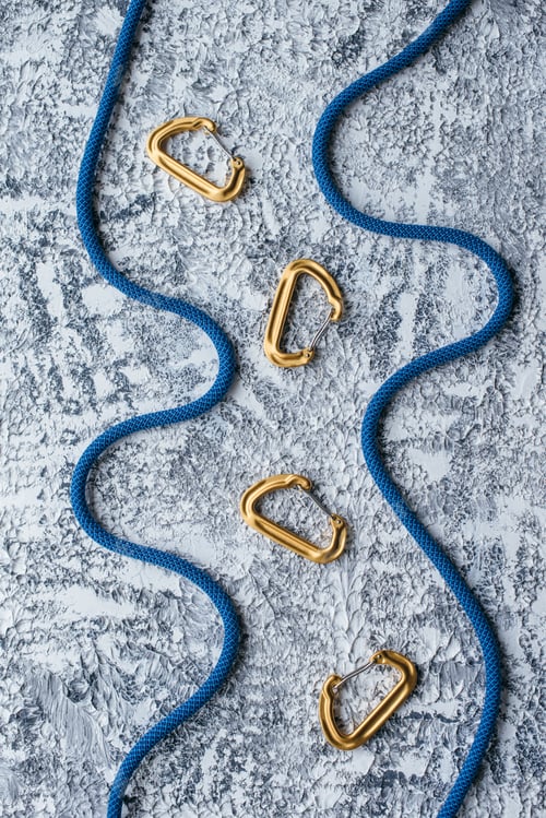 Preview: Isolated photo of climbing equipment. Part of carabiner lying on the white and grey colored table