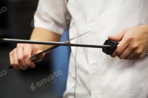 Preview: Close up of a chef sharpening a knife with a honing steel.