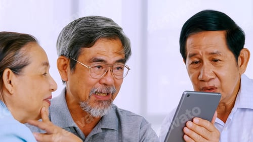 Preview: Group of senior friends using tablet computer in a retirement home