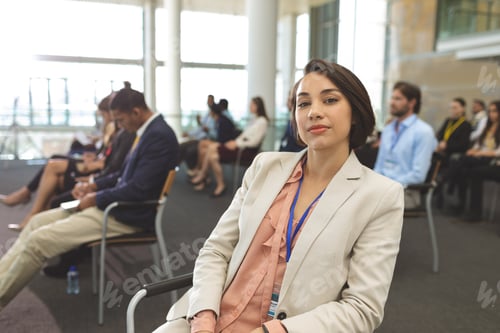 Preview: Front view of young mixed race businesswoman looking at camera during seminar in office building