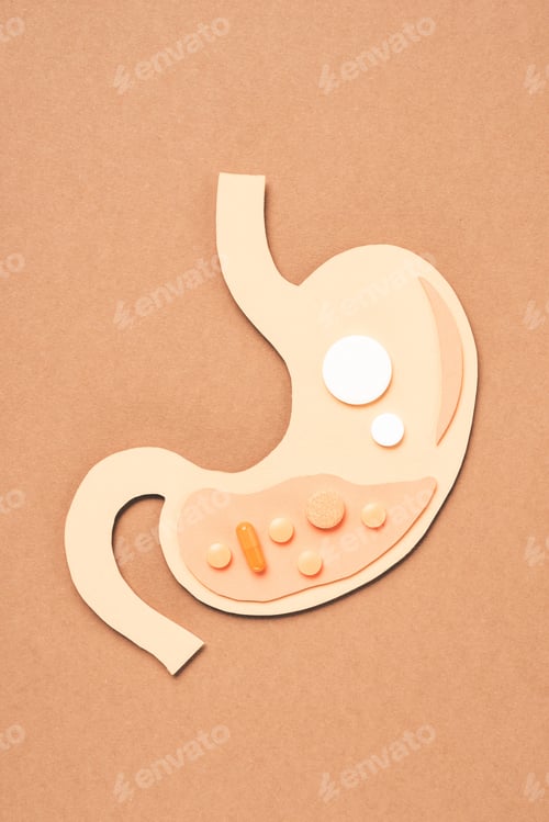 Preview: top view of human stomach with different pills on beige