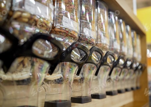 Preview: row of jars with nuts and seeds at grocery store