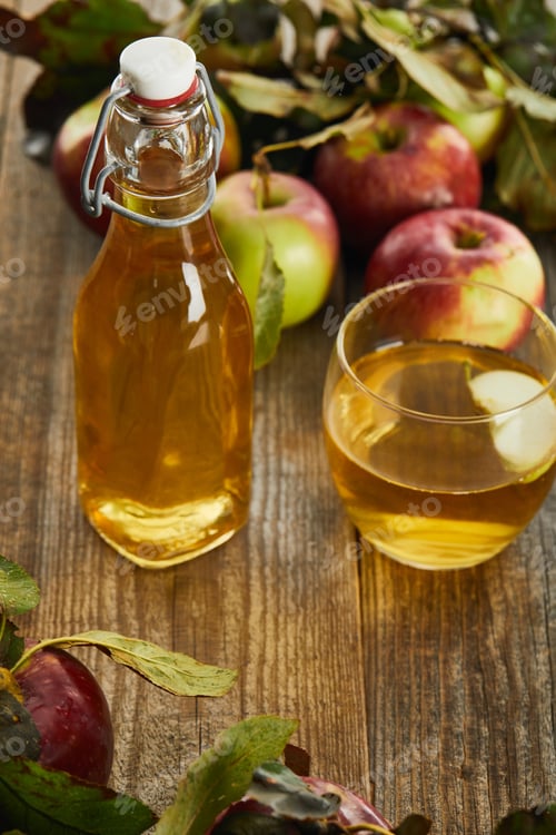 Preview: bottle of fresh cider near glass and apples on wooden surface