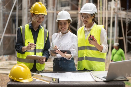 Preview: architector and engineers with draft plan of building and tablet computer talking on constructing