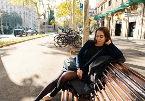 Preview: beautiful girl sitting on a bench in the park in europe