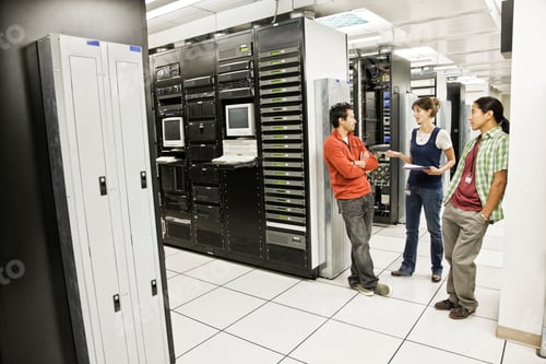 Preview: Three multi-ethnic technicians working in a large computer server room.