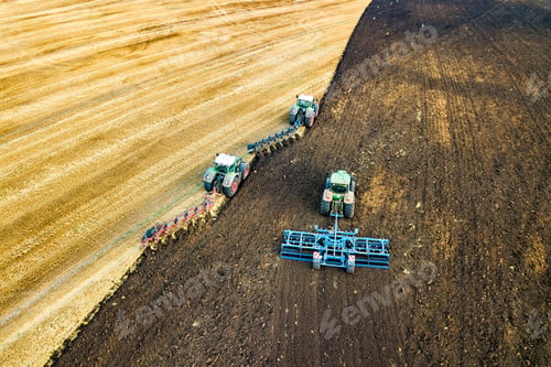 Preview: Aerial view of a tractor plowing black agriculture farm field after harvesting in late autumn