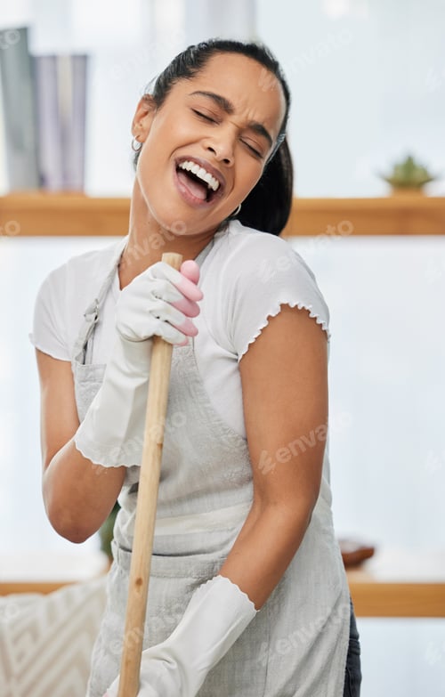 Preview: Shot of an attractive young woman standing and singing while using a broom to sweep her home