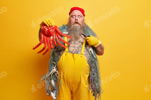 Preview: People sudden reaction concept. Bearded overweight male seafarer holds big red octopus stares with s