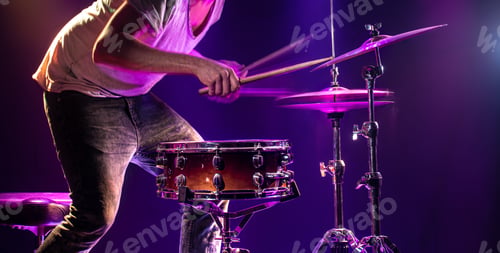 Preview: The drummer plays the drums. Beautiful blue and red background, with rays of light.