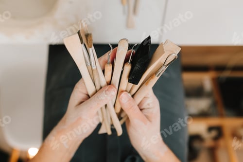 Preview: Potter holds tools for clay sculpting. Wooden instruments for shaping ceramic crockery