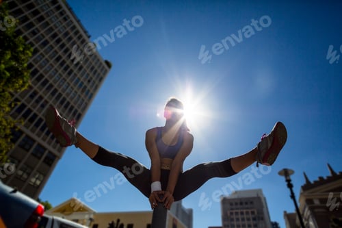 Preview: Athletic woman vaulting over bollard in the city
