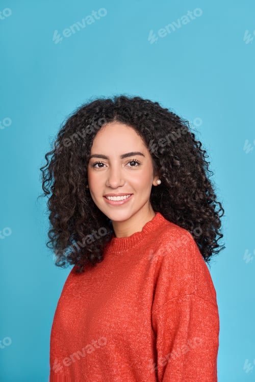 Preview: Young smiling latin woman standing isolated on blue background, portrait.