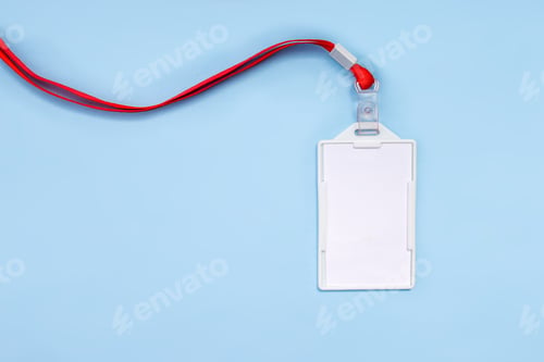 Preview: Top View Of Blank ID Badge With Red Lanyard Lying Diagonally On Blue Background