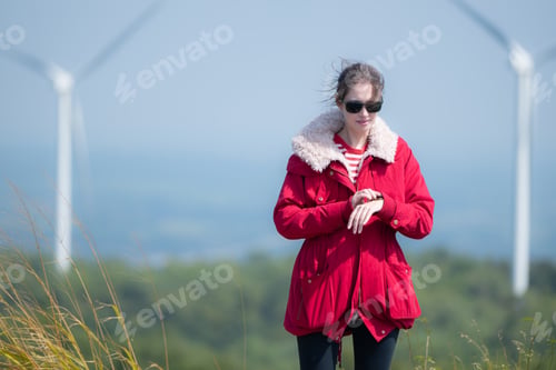 Preview: On the background of windmills, A young woman in a red jacket is enjoying her winter vacation.