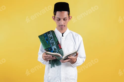 Preview: Muslim Man Wear White Shirts with Traditional Islamic Ornaments and Prayer Mat while Reciting Quran