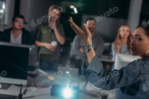 Preview: young people watching presentation in modern office, woman pointing on screen