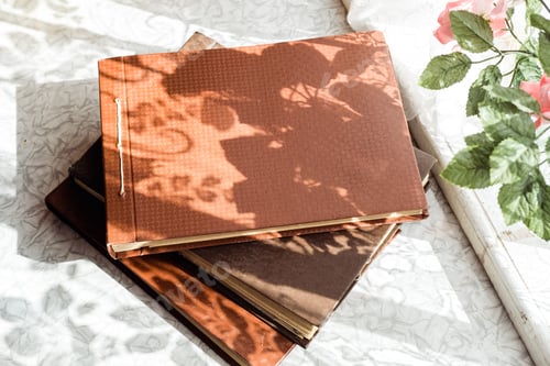 Preview: old brown photo albums are stacked on the table by the window, top view