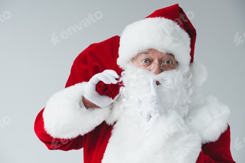 Preview: santa claus holding bag and gesturing for silence isolated on white