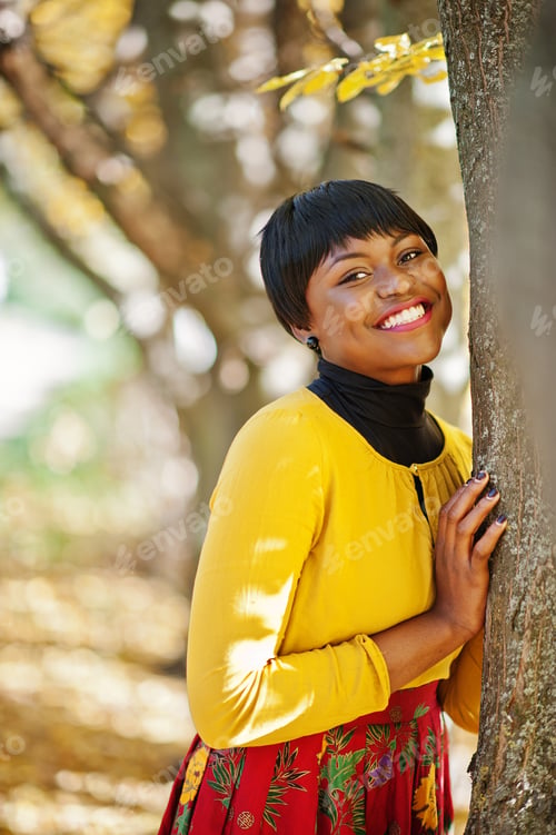 Preview: African american girl at yellow and red dress at golden autumn fall park.
