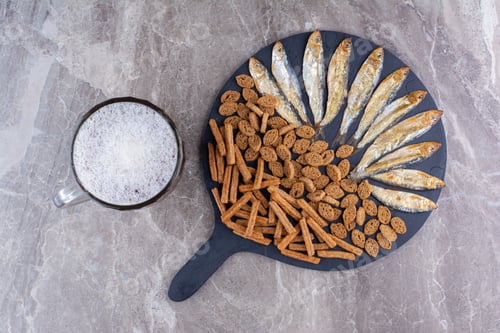 Preview: Various snacks and glass of beer on marble surface