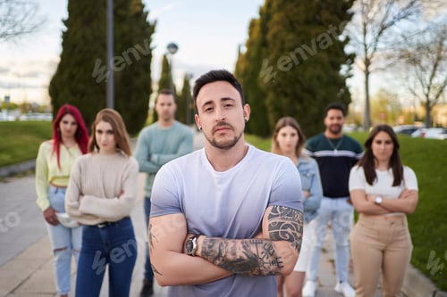 Preview: Man looking serious at the camera while standing in front of a group of people.