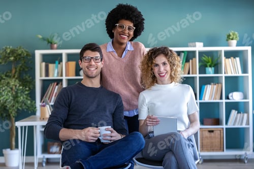 Preview: Casual young business people looking at camera while working in the new office.