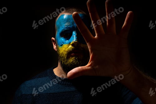 Preview: Stop war, conflict Ukraine and Russia. Portrait of a young man with his face painted