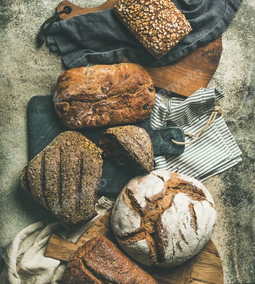 Preview: Flat-lay of various bread loaves on grey background, top view