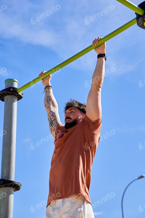 Preview: A young athlete performs pull-ups at an outdoor calisthenics park,