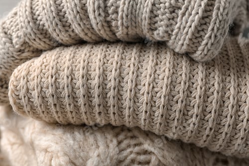 Preview: Stack of folded warm knitted sweaters, closeup