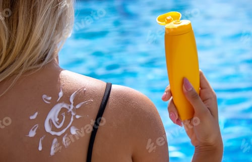 Preview: Girl with a drawing of the sun on her back with sun cream. Relaxation by the pool.