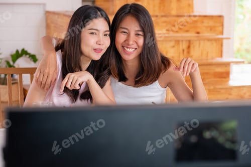 Preview: Happy asian lesbian couple watching television while eating breakfast