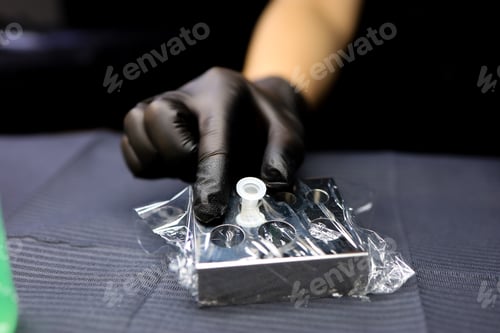 Preview: the hand of the master of permanent makeup holds the cap with the pigment with his fingers