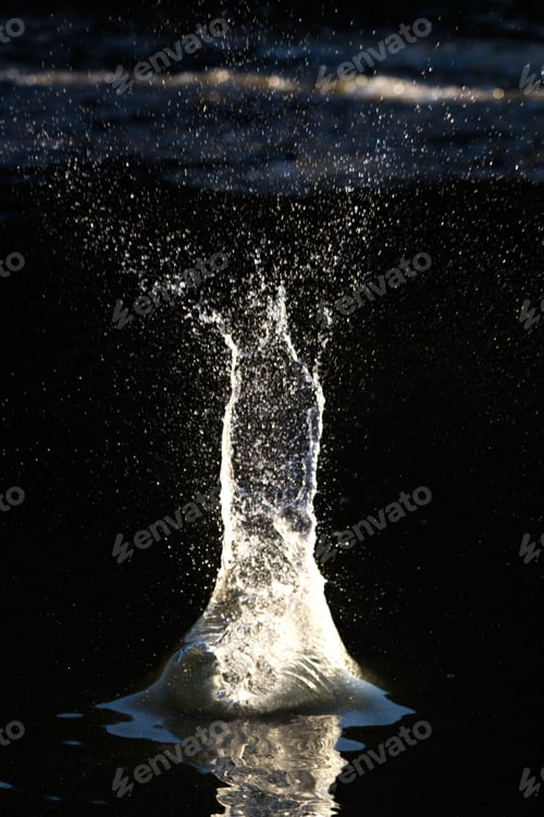 Preview: Dramatic splash of water against the illuminated surface of the sea