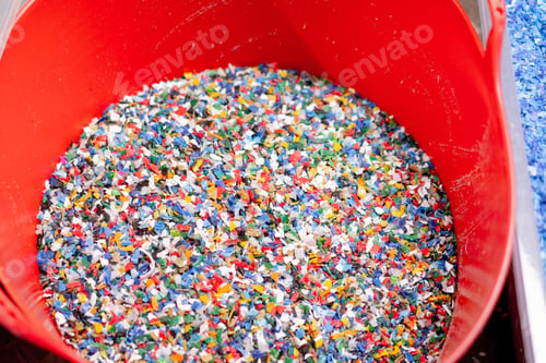 Preview: Close-up shot of shredded plastic caps stored in a special container at waste recycling station