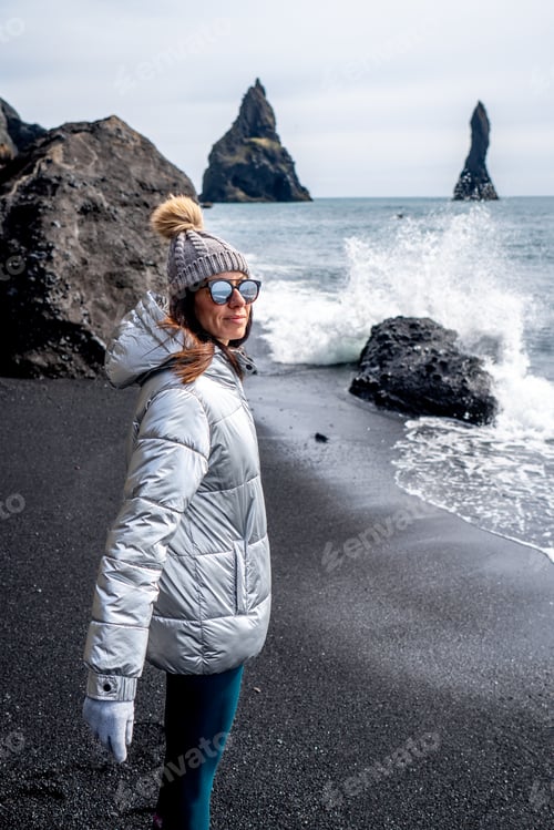 Preview: Woman with silver coat and beanie on the black beach of Reynisfjara, Iceland