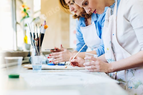 Preview: Two people focused on painting in a bright art studio