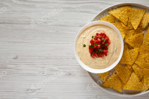 Preview: Homemade cheesy dip in a bowl, yellow tortilla chips, top view. Flat lay, overhead, from above.