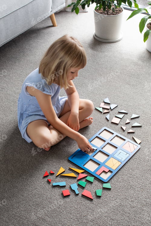 Preview: A cute girl is playing a logical wooden game on the floor in the room. Educational toy.