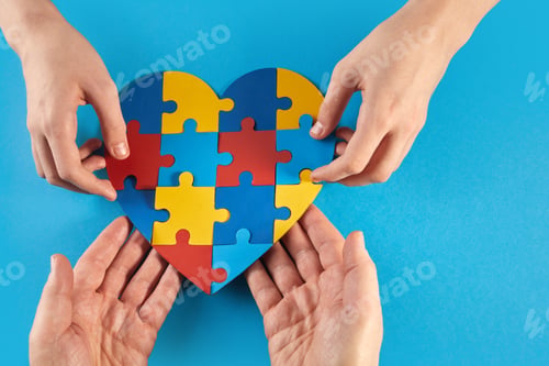 Preview: Father and autistic son hands holding jigsaw puzzle heart shape. World Autism Awareness Day